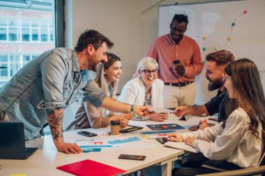 Çeşitli yaratıcı iş adamları modern bir şirketin toplantı odasında birlikte çalışıyorlar. Beyin fırtınası konsepti. Ofis hayatı. Çok ırklı iş arkadaşları. Dövmeli sakallı bir işadamına odaklan..
