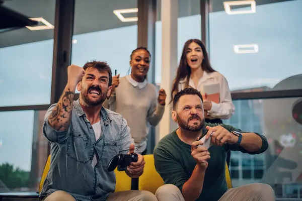 Neşeli çeşitli iş arkadaşları TV konsolunda video oyunları kazanıyor. İşten sonra ofiste joystickle oynuyorum. Mutlu insanlar ofis partisinde eğleniyorlar..