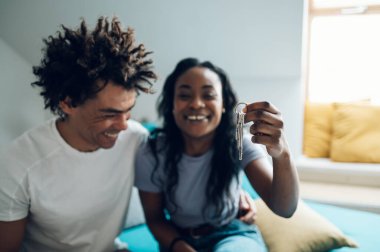 Yeni evlerinin anahtarlarını tutan ve gösteren mutlu Afro-Amerikan çifti. Mülk satın almak. İlk kez gayrimenkul sahipleri. Anahtarlara odaklan..