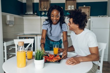 Afro-Amerikan çiftleri sabahları mutfak masalarında oturup sohbet edip kahvaltı ediyorlar. Lezzetli yemek ve portakal suyu..