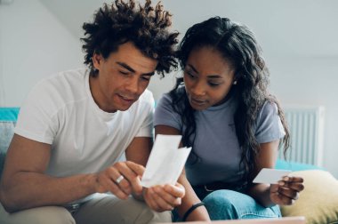 Afrikalı Amerikalı çift hesaplarını evde yapıyorlar ve online ödeme için bir laptop ve kredi kartı kullanıyorlar. İnternetten alışveriş ve alım. Faturalar ve aile bütçesi.