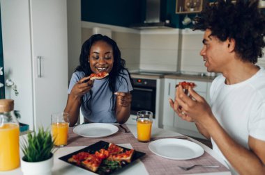 Genç Afro-Amerikan çift sabah birlikte kahvaltı ederken sağlıklı yiyecekler yiyip portakal suyu içiyorlar. Romantik bir sabah. Lezzetli sağlıklı yemek..