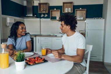Genç Afro-Amerikan çift sabah birlikte kahvaltı ederken sağlıklı yiyecekler yiyip portakal suyu içiyorlar. Romantik bir sabah. Lezzetli sağlıklı yemek..