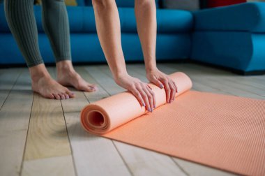 Çekici genç kadın elleri oturma odasında çalıştıktan sonra pembe yoga ya da spor paspası katlıyor. Sağlıklı bir hayat, sağlıklı kavramları korumak. Yas tutma rutini.