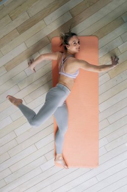 Evdeki spor minderinde yoga yapan atletik bir genç kadının en iyi görüntüsü. Yüksek açı. Spor ve sağlıklı yaşam tarzı kavramı. Rüzgar hafifletme pozu, Ardha Pavanmuktasana.