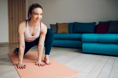 Güzel genç bir kadın yerde spor paspasına uzanıyor ve evde yoga yapıyor. Sağlıklı yaşam tarzı kavramı.