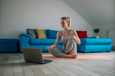Fitness kadın blogcusu bilgisayarına video kaydediyor ve evde oturma odasında antrenman yapıyor. Yaşam tarzını etkileyen spor ve eğlence konsepti.