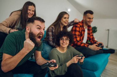 Gülümseyen bir grup arkadaş evde oyun oynuyor ve eğleniyorlar. Gençler internetteki yeni teknoloji konsoluyla eğleniyor.