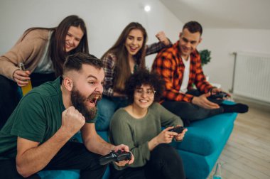 Evde dijital oyunlar oynayan neşeli bir arkadaş grubu. Bluetooth video oyun kumandası. Dost canlısı rakipler. Birlikte eğleniyoruz..