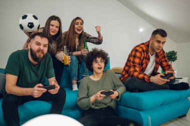 Evde video oyunu oynayan bir grup arkadaş. joysticklerle video oyunu oynuyorum. Arkadaşlık, teknoloji ve oyun konsepti.