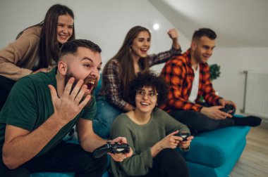 Evde video oyunu oynayan bir grup arkadaş. joysticklerle video oyunu oynuyorum. Arkadaşlık, teknoloji ve oyun konsepti.