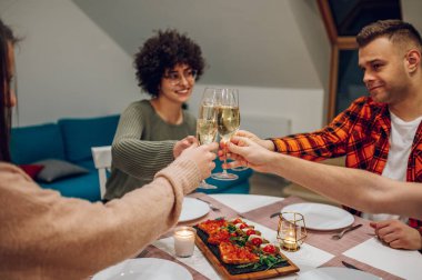 Mutfaktaki bir masanın etrafında toplanmış bir grup arkadaş birlikte yemek yiyor ve kadeh kaldırırken iyi vakit geçiriyorlar. Lokanta konsepti sırasında kutlama.
