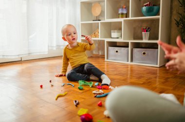 Renkli kille oynayan bir çocuğun portresi. Çocuklar oynar. Küçük çocuk kil ya da plastiğin kalıbını çıkarırken nesneler ve şekiller yaratıyor. Bebek ve bebek için eğitici bir oyun. Ev ya da anaokulu.