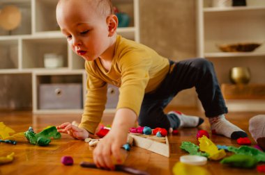 Yerde renkli kille oynayan bir çocuğun yakın çekimi. Çocuklar oynar. Küçük çocuk kil ya da plastiğin kalıbını çıkarırken nesneler ve şekiller yaratıyor. Bebek ve bebek için eğitici bir oyun. Boşluğu kopyala.