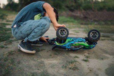 Bir çocuk doğada çömeliyor ve bozuk bir arabayı tamir ediyor. Küçük bir tamirci doğada zaman geçirirken oyuncak arabasını tamir ediyor. Bir çocuk oyuncak arabasını inceliyor ve arızayı bulmaya çalışıyor..