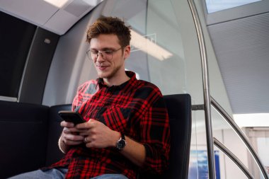 Akıllı telefon kullanırken işe ya da okula trenle ya da metroyla giden yakışıklı bir adam. Hippi adam sürüş sırasında e-posta okuyor ya da cep telefonuna mesaj yazıyor. Toplu taşıma.