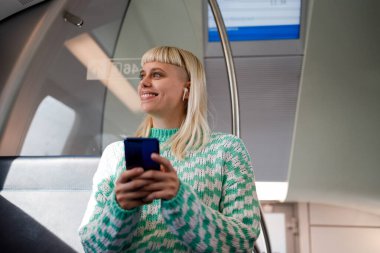 Okula gidip gelen bir kadının portresi ya da akıllı telefon kullanırken trende ya da metroda çalışan bir kadının portresi. Genç bir kadın sürüş sırasında e-posta okuyor ya da cep telefonuna mesaj yazıyor. Boşluğu kopyala.