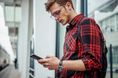 Akıllı telefon kullanırken tren ya da metro bekleyen yakışıklı bir adam. Hippi adam sürüş sırasında e-posta okuyor ya da cep telefonuna mesaj yazıyor. Toplu taşıma konsepti. Boşluğu kopyala.