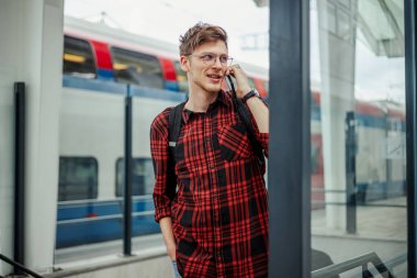 Akıllı bir telefonla konuşurken işe trenle gidip gelen yakışıklı bir adam. Hipster adam tren istasyonuna varana kadar telefonuyla konuşuyor. İnsanlar seyahat konsepti