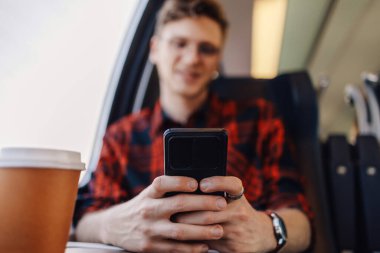 Yolculuğu sırasında trende telefonla mesaj yazan bir yolcuyu kapat. Bir hipster yolcusu trende oturuyor ve uzak bir yerde seyahat ederken ağrı kesici olarak telefon uygulaması kullanıyor..