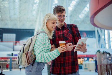 Metro istasyonunda durup tablete bakan genç bir z hipster çiftin portresi. Metroda ya da metro istasyonunda zaman çizelgesini kontrol ederken genç bir çift dokunmatik ekranda gülümsüyor. Boşluğu kopyala.