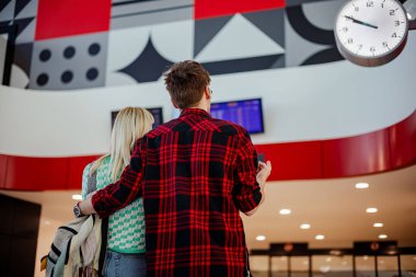 Tren istasyonunda bekleyen ve zaman çizelgesine bakan genç bir banliyö çalışanının arka görüntüsü. Metro istasyonunda durup trenlerini beklerken tren tarifesine bakan yolcuların arkası. Boşluğu kopyalayın.
