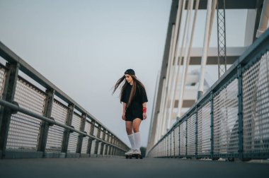 Köprüde sörf tahtasıyla gezen genç bir kadın