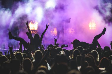 Silhouette of a crowd on a rock concert while crowd surfing and suing smartphone clipart