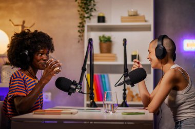 İki çok ırklı kız bir yayın stüdyosunda podcast yapıyor. Kızlar küçük bir evde kayıt stüdyosunda oturup podcast yapıyorlar. Video içeriği oluşturan ırklar arası podcasterler.