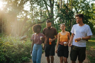 Çifte randevuda olan iki çok kültürlü çift güneşli bir yaz gününü doğada birlikte geçiriyorlar. Genç hippi insanlar içki içiyor ve birlikte eğleniyorlar. İlişki, flört. Boşluğu kopyala.