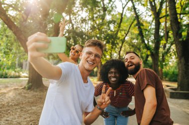 Bir grup çok ırklı arkadaş birlikte vakit geçirirken dışarı çıkıp selfie çekiyorlar. Genç alt kültür arkadaşları arkadaşlıklarını resimde gösteriyorlar. Bir grup arkadaş hayatı kutluyor..