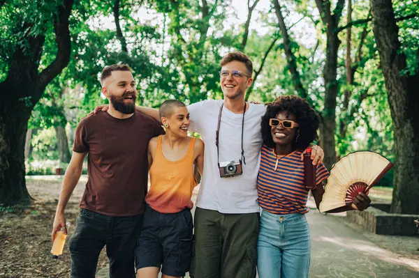 stock image Happy group of multicultural friends are hugging and taking a walk in park while celebrating unity, diversity and mother earth's day. Diverse friends having fun in nature. Eco friends walking in park.