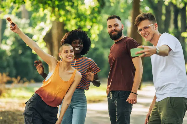 Küçük bir grup çok kültürlü hippi arkadaş bir parkta birlikte durup selfie çekiyorlar. Şehirli trend arkadaşları şehir parkında kaliteli zaman geçiriyorlar. Birkaç iyi arkadaş hatıralar yaratıyor..