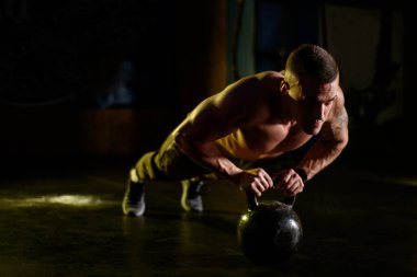 Salonda kettlebell tutarken şınav çeken yakışıklı kaslı adam.