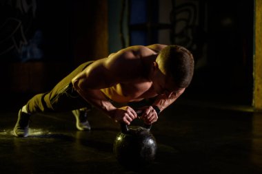 Spor salonunda davulda şınav çeken bir gencin fotoğrafı.