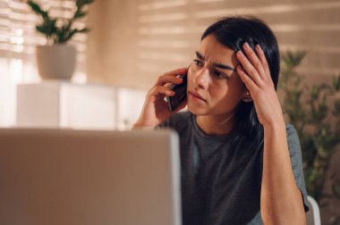 Yüzünde endişeli bir ifadeyle elini başının üstüne koyarak cep telefonuyla konuşan stresli bir iş kadınının portresini yakından çek. Hüsrana uğramış genç patron işten kötü haberler alıyor..