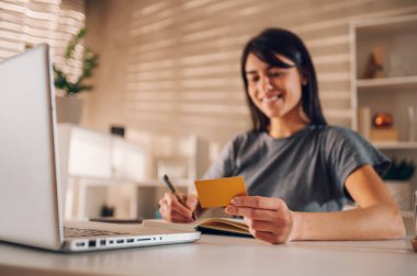 Bir iş kadınının gülümserken kredi kartını elinde tutarken görüntüsü bulanıklaştı. Parmaklarının arasındaki kredi kartına odaklan. Aletleri ve online bankacılığı alışveriş için kullanmak. Boşluğu kopyala