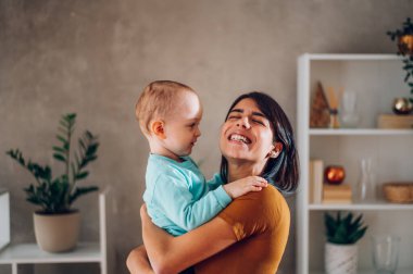 Küçük oğluyla hafta sonu eğlenen, onu kucaklayan ve kucağında taşıyan bir anne. Önemseyen mutlu anne, küçük çocuk ile eğleniyor. Boşluğu kopyala.