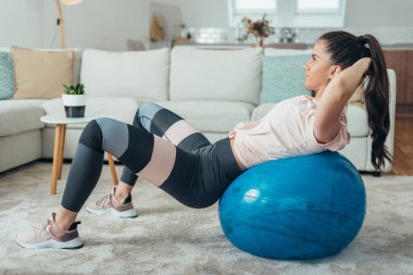 Evde antrenman yaparken spor salonunda mekik çeken çekici bir kadın.