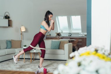 Direniş bandı kullanırken evde çalışan çekici bir genç kadın.