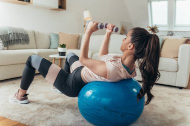 Spor kıyafetli genç sarışın bir kadının spor salonunda ağırlık kaldırırken biraz mekik çekişini izledik.