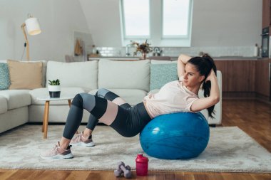 Evdeki spor salonunda mekik çeken güzel bir genç kadın.