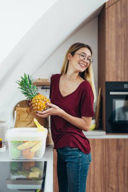 Mutfağında duran gülümseyen genç bir kadının portresi.