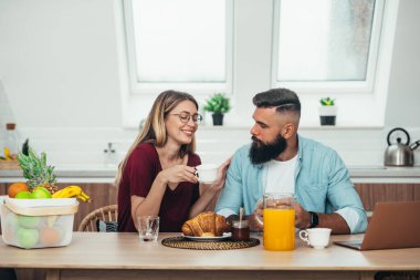 Genç ve güzel bir çift kahve içerken kahvaltı yapıyorlar.