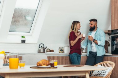 Evdeki mutfakta kahve içerken romantik bir an yaşayan genç ve çekici bir çift.