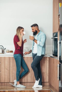 Sevecen genç bir çiftin kahve içerken mutfakta dinlenmesi.