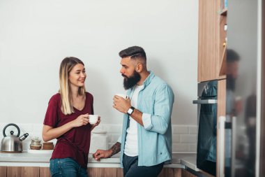 Genç ve güzel bir çift evdeki mutfakta kahve içerken...