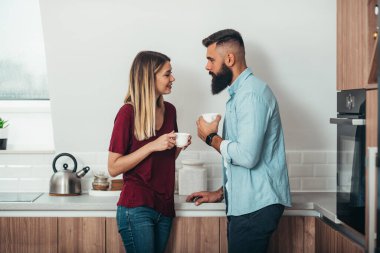 Evdeki mutfakta kahve içerken romantik bir an yaşayan genç ve çekici bir çift.