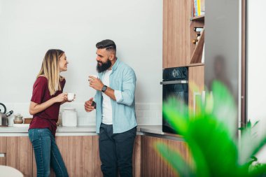 Evdeki mutfakta kahve içerken romantik bir an yaşayan genç ve çekici bir çift.