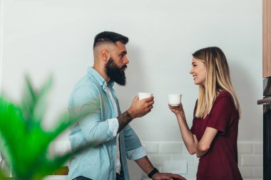 Genç ve güzel bir çift evdeki mutfakta kahve içiyor.